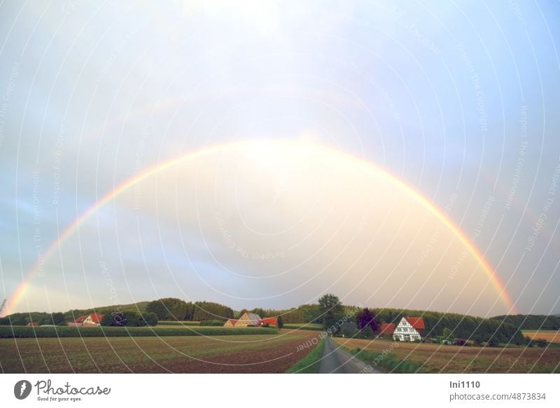 Regenbogen am Himmel Natur Landschaft Landwirtschaft Felder Häuser Straße Wald Abendstimmung Sonne Licht Regenbogenfarben Naturphänomene Naturschauspiel