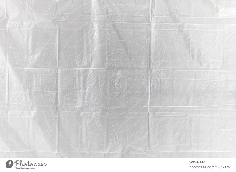 Eine weiße Plastikplane mit vielen Falten zum Schutz vor Blicken und Staub Plane geknittert gefaltet geometrisch hell Kunststoff PVC rechtecke Hintergrund