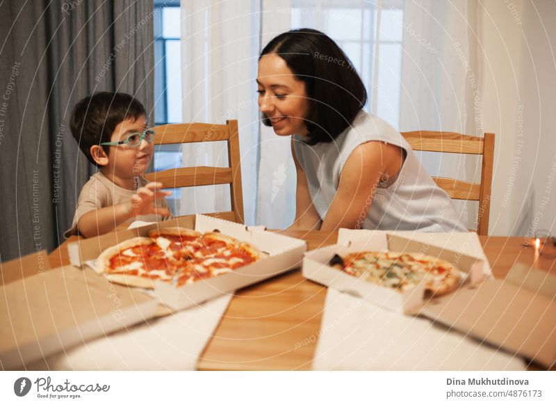 Mutter und Sohn essen eine Pizza zu Hause. Pizzalieferung. Echte Menschen essen zu Abend, lächeln und essen Pizza Comfort Food. Versand Lebensmittel Küche