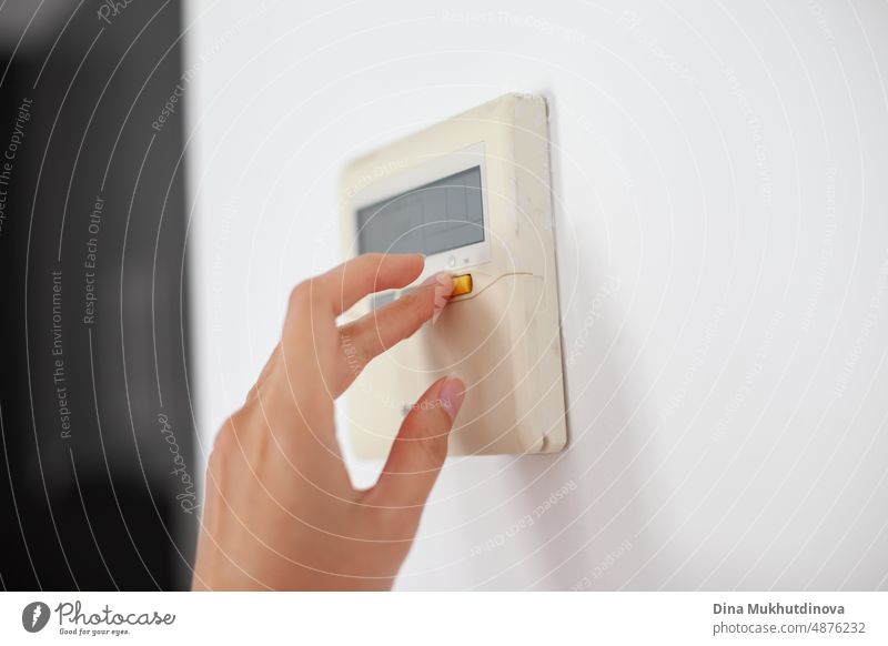 Eine Hand drückt eine Taste am Smart-Home-System. Klimatisierungssystem für Komfort zu Hause. Modernes Haus und digitale Steuerung.  Smart-Home-Gerät und Konsole.