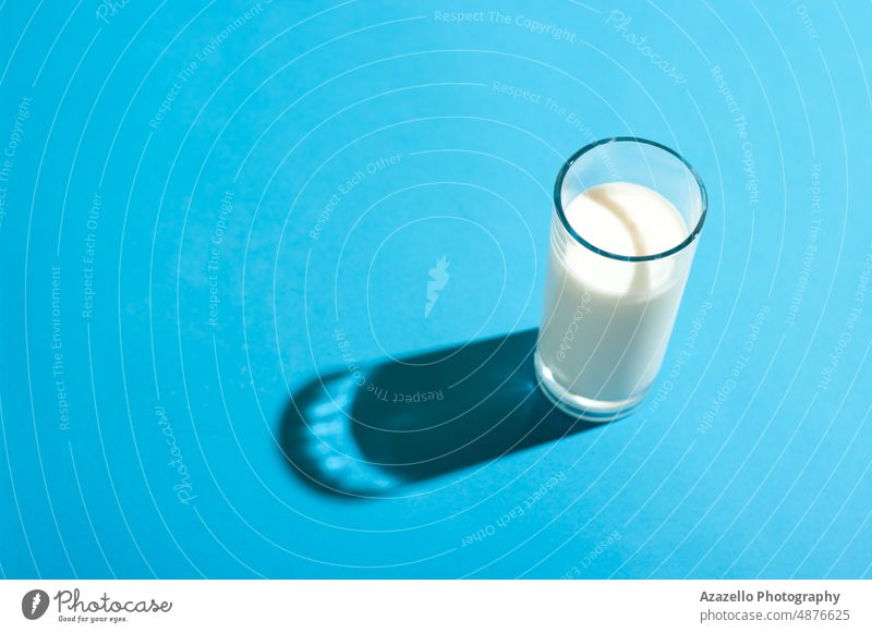 Glas Milch unter dem hellen Licht mit hartem Schatten auf blauem Hintergrund. melken Pastell Stillleben Minimalismus abstrakt Gesundheitswesen Baby Getränk