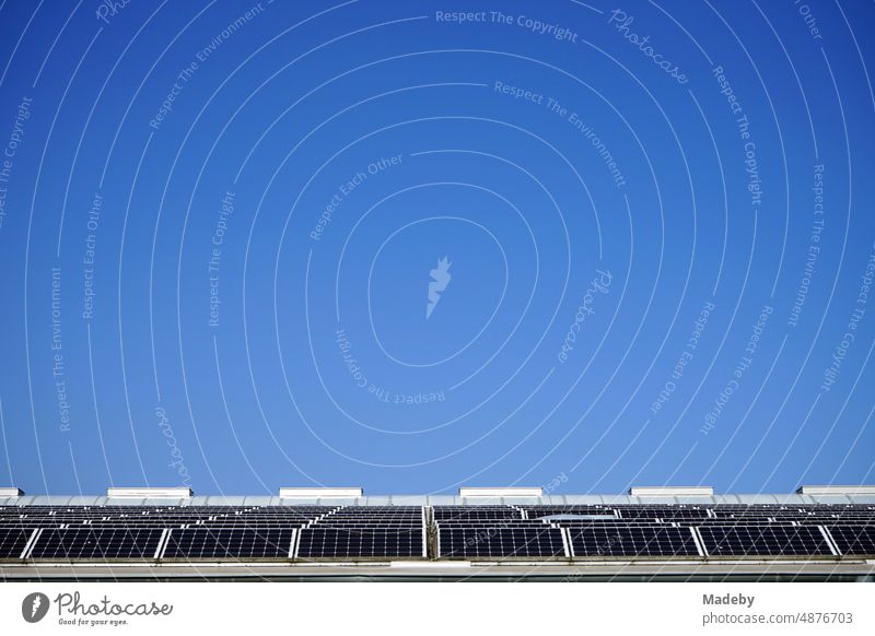 Photovoltaik mit Solarzellen auf dem Dach einer großen Lagerhalle vor blauem Himmel im Sonnenschein in Ibbenbüren im Kreis Steinfurt in Westfalen himmel solar