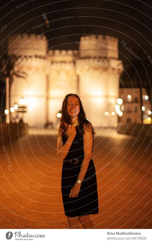 Glückliche Frau zu Fuß im historischen Zentrum der Stadt mit Lichtern. Glücklich lächelnd, auf dem Weg zur Party. Junge und schöne Touristin in Spanien. Nacht