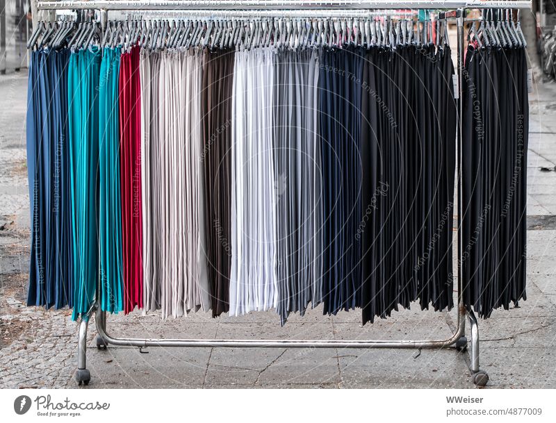An der Stange auf dem Wochenmarkt hängen gleichförmige Hosen in verschiedenen Farben Kleidung Markt verkaufen Angebot Konfektion Bügel bunt anbieten Stand