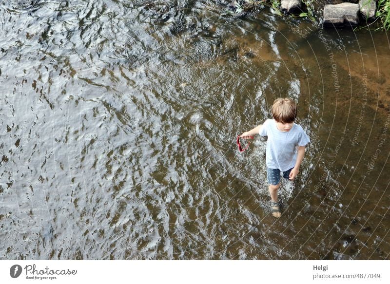 Junge  schlendert lässig mit Sonnenbrille in der Hand am Ufer der Fulda durchs Wasser Mensch Kind 8 Jahre Fluss Flussufer Vogelperspektive Natur Abkühlung