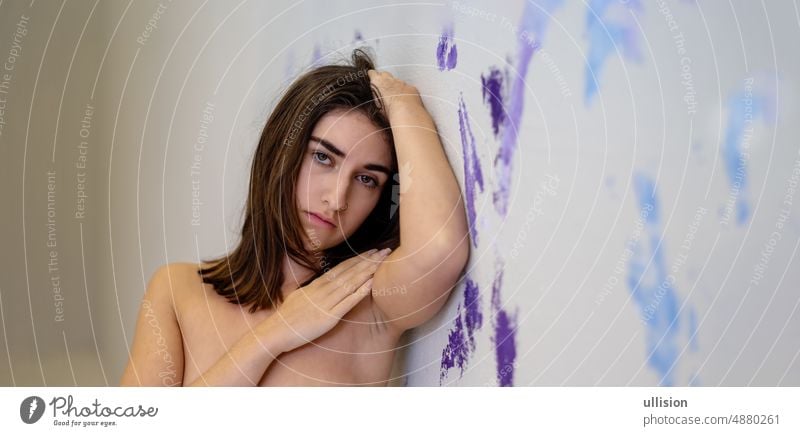 Porträt einer jungen sexy verführerischen brünetten Frau, die auf dem lila, violetten, blauen künstlerisch bemalten Studiowandhintergrund steht Wand Hintergrund