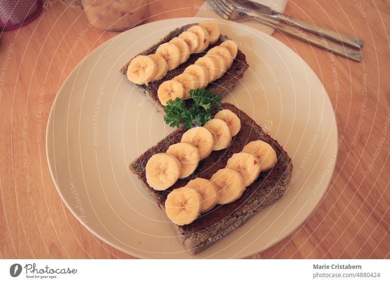 Vollkornbrot mit Schokoladenaufstrich und Bananenscheiben für ein gesundes veganes Frühstück und einen gesunden, nachhaltigen Lebensstil Vegane Ernährung