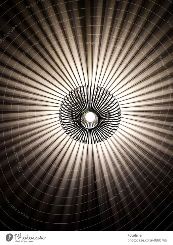 Die Deckenlampe aus geschwungenem Metall malt ein irres Muster an die Zimmerdecke. Lampe Licht Design Beleuchtung Glühbirne leuchten Lichtspiel Schatten Spirale