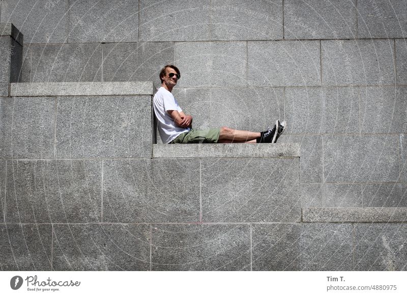 ein Mann sitzt auf einer Granitbrüstung Sonnenbrille kurze hose Berlin Stadtschloss Mitte Außenaufnahme Farbfoto Stadtzentrum Hauptstadt Berlin-Mitte