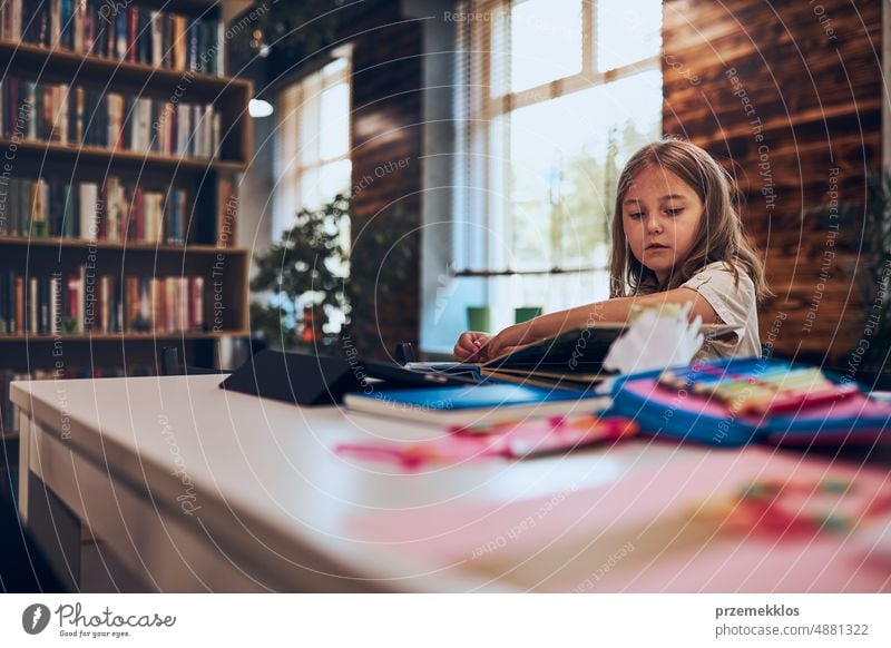 Schulmädchen beim Lernen, Spielen, Puzzeln und Lesen in der Schulbibliothek. Grundschülerin beschäftigt sich mit Buch und Puzzle. Kind neugierig Schule Rücken
