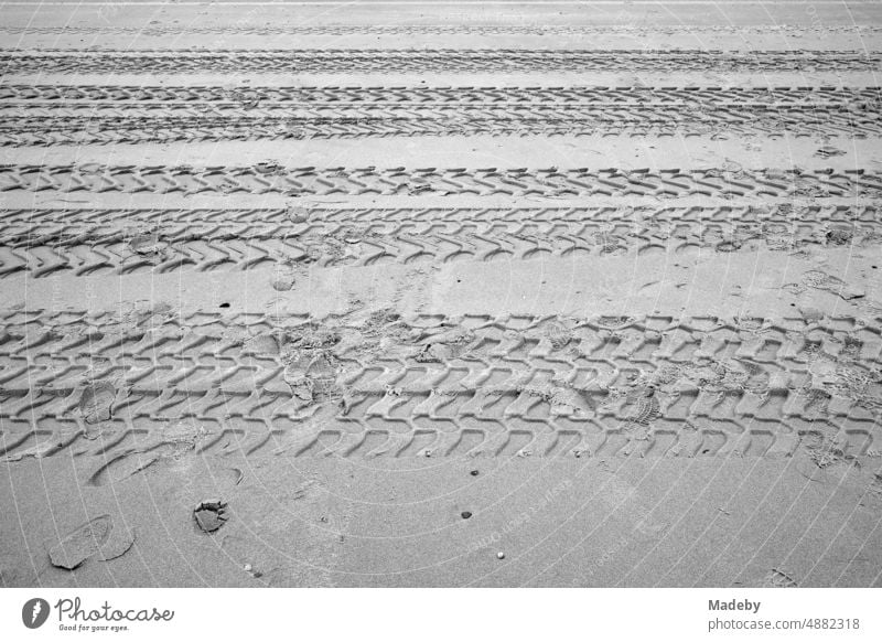 Grobe Reifenspuren im Sand am Strand in Knokke-Heist an der Nordsee bei Brügge in Westflandern in Belgien, fotografiert in klassischem Schwarzweiß Anordnung