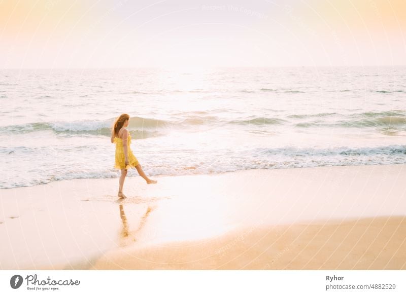Goa, Indien. Junge kaukasische Frau im gelben Kleid, die am Meeresufer im Sommersonnenlicht spazieren geht Arabisches Meer Indischer Ozean Asien schön Kaukasier