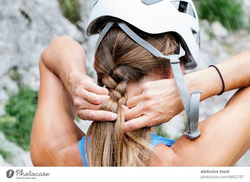 Frau mit Schutzhelm beim Binden eines Zopfes in Vorbereitung auf eine Wanderung Geflecht vorbereiten Wanderer Nahaufnahme Rückansicht braune Haare