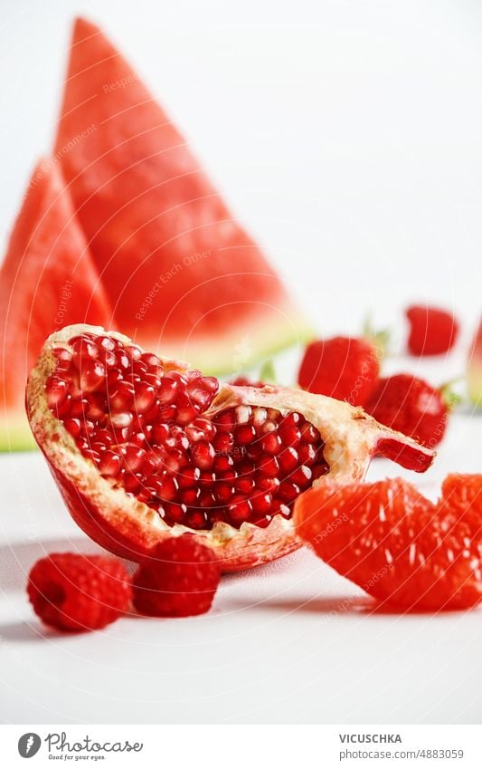 Nahaufnahme eines Viertels Granatapfel, Wassermelone, Himbeeren und Grapefruit auf weißem Hintergrund lecker abschließen weißer Hintergrund Gesundheit süß rot