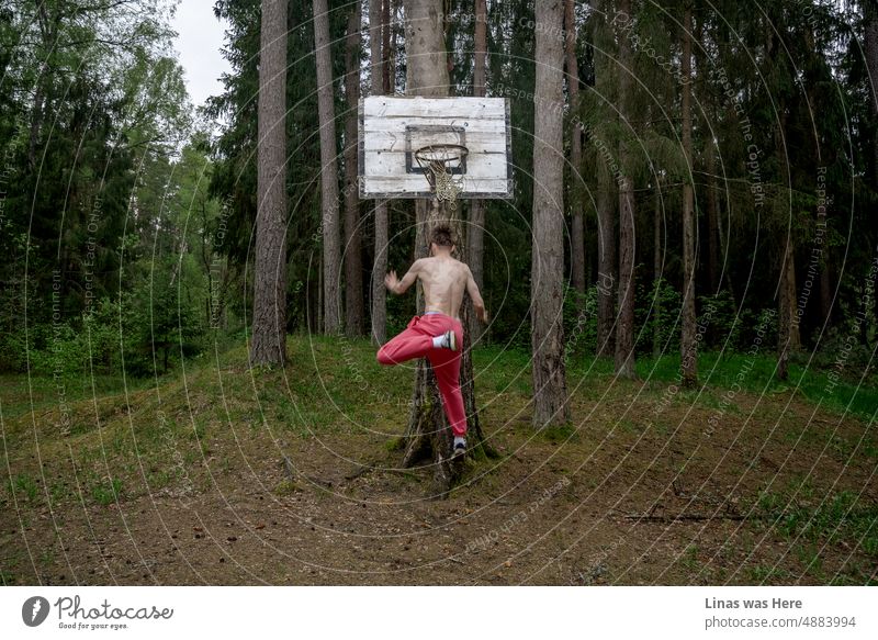 Spaß haben im Wald. Wilder Junge mit rosa Hosen spielt eine Art Basketball. Sport in einem Wald an einem heißen Sommertag. rostig Wälder Muskeln Sommerzeit