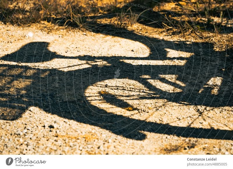 Schattenbild eines Damenfahrrads auf Kiesboden. Fahrrad-Schatten Fahrradfahren Verkehr Verkehrsmittel Farbfoto Menschenleer Wege & Pfade Katzenauge