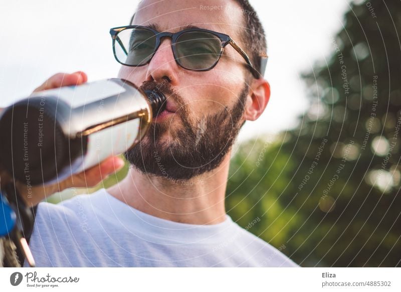 Mann trinkt ein Bier aus der Flasche trinken Biertrinken Alkohol Getränk Bierflasche Durst Brille Bart jung Sommer Craft-Bier Genuss Nahaufnahme draußen