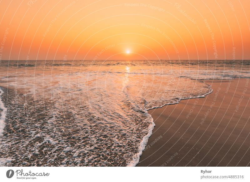 Sonnenuntergang Sonne über Meer. Natürliche Sonnenaufgang Himmel warme Farben über Ripple Meer. Ozean Wasserschaum Waschen Sandstrand bei Sonnenuntergang schön