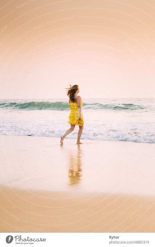 Goa, Indien. Junge kaukasische Frau im gelben Kleid, die das Leben genießt und in Richtung der Meereswellen läuft Arabisches Meer Indischer Ozean Asien schön