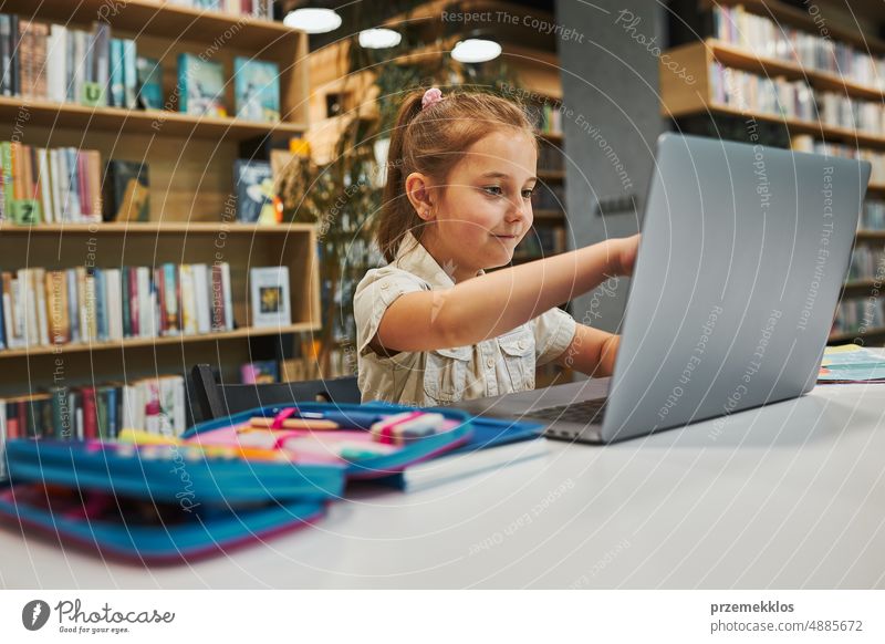 Engagierte Schülerin macht ihre Hausaufgaben mit dem Laptop in einem Club nach der Schule in der Grundschule. Zurück zur Schule. Kind nutzt Technologie im Informatikunterricht. Kluges Mädchen lernt von Bildungsanwendung in der Schule