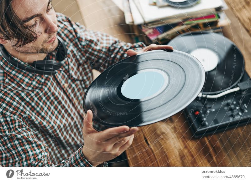 Mann hört Musik von einer Schallplatte. Abspielen von Musik von einer analogen Platte auf einem Plattenspieler. Genießt Musik aus einer alten Sammlung. Retro und Vintage