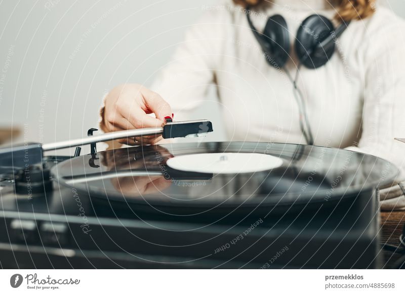Junge Frau hört Musik von einem Schallplattenspieler. Spielt Musik auf einem Plattenspieler. Frau genießt Musik aus alter Plattensammlung zu Hause hören