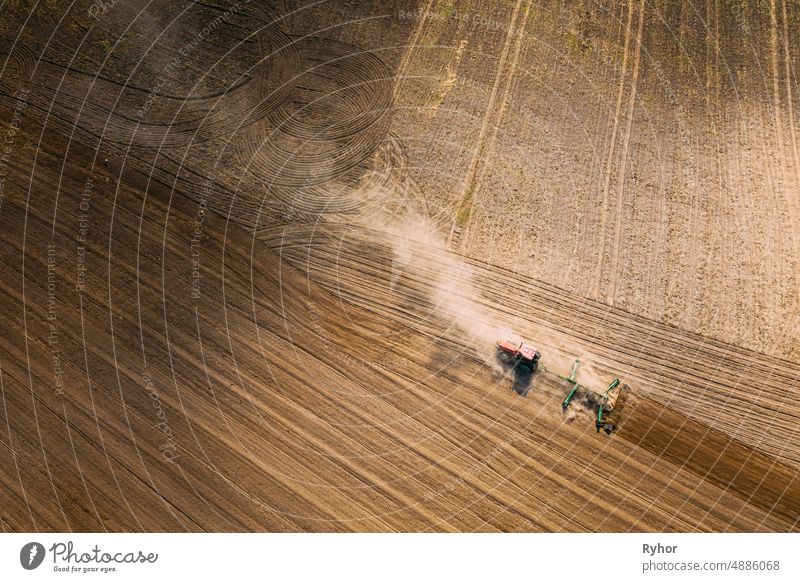 Luftaufnahme. Traktor pflügt Feld. Beginn der landwirtschaftlichen Frühjahrssaison. Cultivator Pulled By A Tractor In Countryside Rural Field Landscape. Staub steigt von unter Pflügen