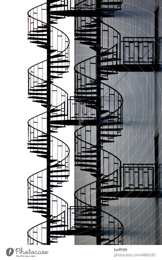 elegante Wendeltreppen an nüchternen Industriefassade ästhetisch Kurve Silhouette Treppe Fassade Notausgang Stahl Linie DNA Industrieanlage Lagerhalle Wand