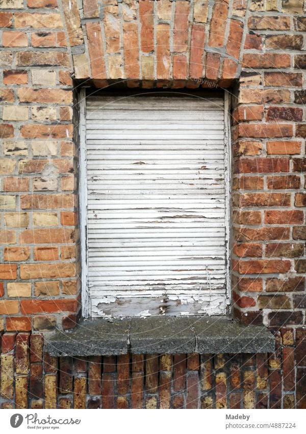 Altes Fenster mit heruntergelassenem weißen Rollladen in altem Mauerwerk aus rotbraunem Backstein eines Wohnhaus in Knokke-Heist an der Nordsee bei Brügge in Westflandern in Belgien