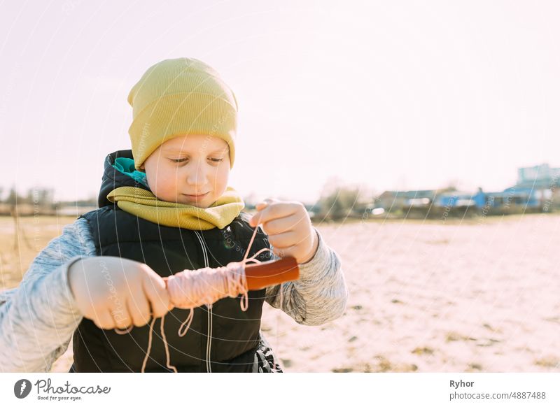 Junge von 6-7 Jahren nimmt eine Schnur von einem Drachen auf. Angenehme Aktivität an der frischen Luft an einem sonnigen Frühlings- oder Herbsttag aktiv schön