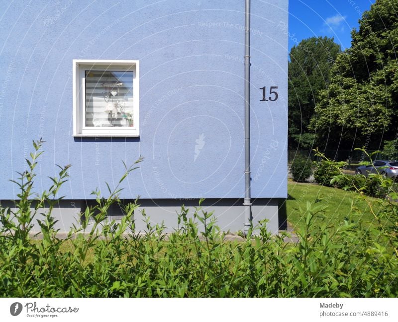 Sanierte blaue Fassade mit Wärmedämmung und grünem Vorgarten im Sommer bei Sonnenschein in einer Wohnsiedlung in Oerlinghausen bei Bielefeld am Hermannsweg im Teutoburger Wald in Ostwestfalen-Lippe