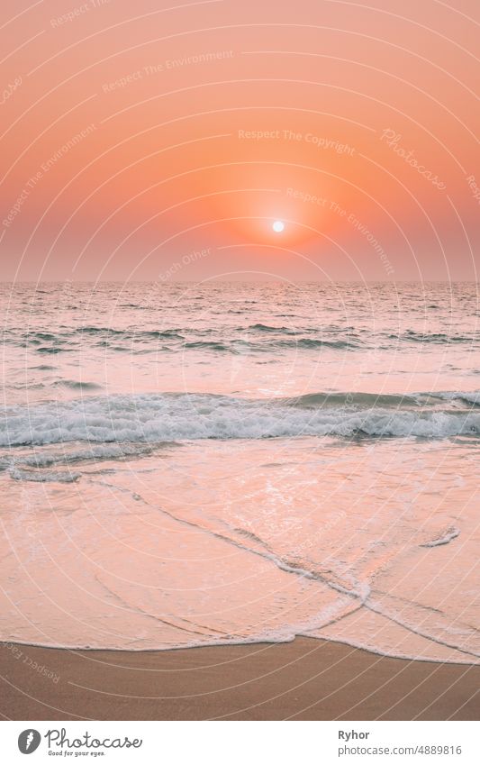 Sonnenuntergang Sonne scheinen über Meer. Natürliche Sonnenaufgang Himmel warme Farben über Ripple Meer. Ocean Water Foam Splashes Waschen Sandstrand schön hell