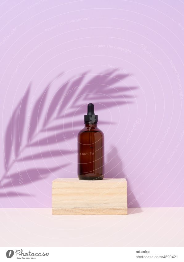 Braune Glasflasche mit einer Pipette auf lila Hintergrund. Palmenblatt Schatten Körperpflege Podium Flasche Kosmetik Tropfer Blatt Hautpflege Handfläche Produkt