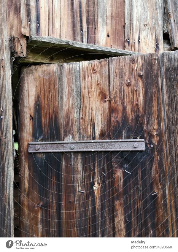 Alte Stalltür aus braunem Holz mit rostigen Eisen auf einem alten Bauernhof in Rudersau bei Rottenbuch im Kreis Weilheim-Schongau im Pfaffenwinkel in Oberbayern