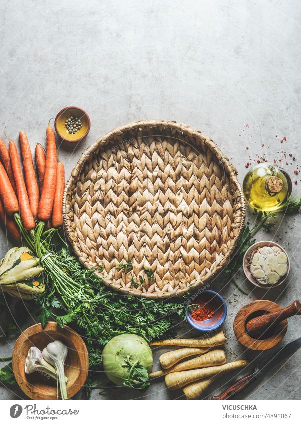 Gesundes Essen Hintergrund mit runden Tablett mit verschiedenen Gemüse, Öl, Kräuter und Gewürze auf grauem Beton Küchentisch Gesundheit Lebensmittelhintergrund
