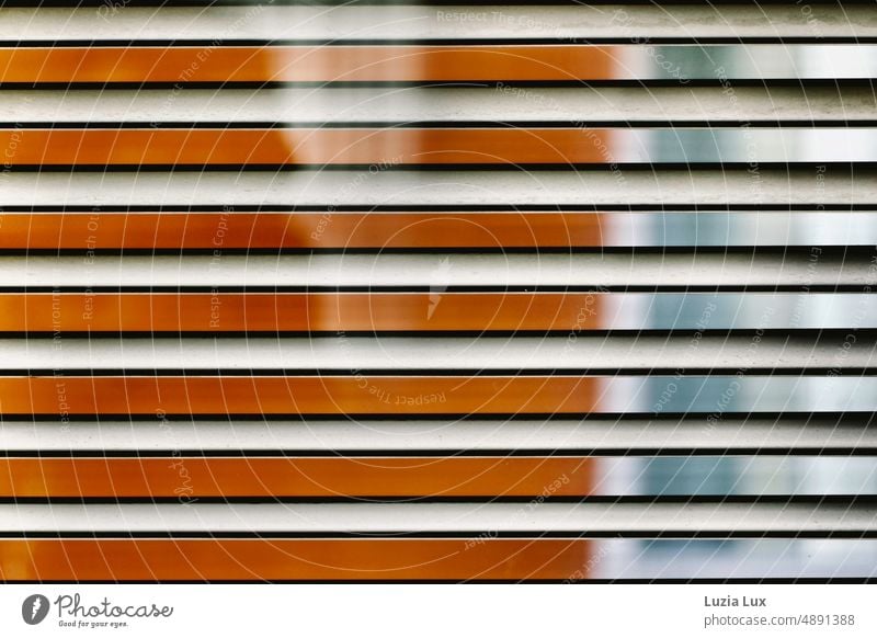 Streifen orange und blau, Blick durch eine Jalousie bei greller Sonne auf die gegenüberliegende Haus- und Fensterfassade gestreift Licht Sonnenschein