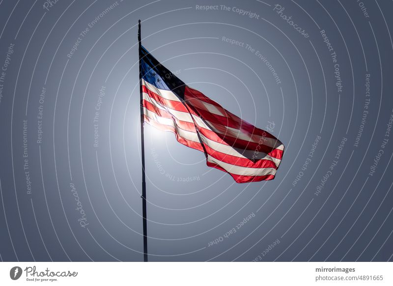 Vereinigte Staaten von Amerika Flagge weht im Wind mit hellen Tag Himmel Sonne hinter ihm Wehen der amerikanischen Flagge Veteranentag Vorsitzender Feiertag