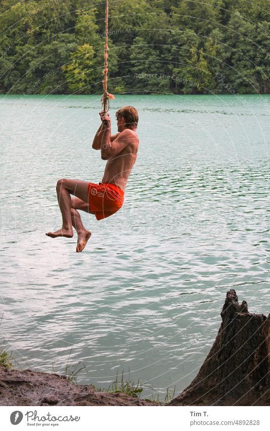 ein Mann schwingt an einem Seil um in den See zu springen liepnitzsee Brandenburg Wasser ruhig Natur Außenaufnahme Seeufer Farbfoto Landschaft Baum Tag Idylle