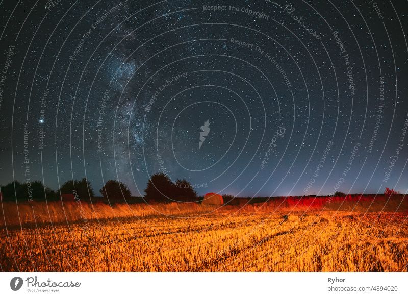 Milchstraße Galaxie in der Nacht Sternenhimmel über Heuhaufen im Sommer landwirtschaftlichen Bereich. Nacht Sterne über ländliche Landschaft mit Heuballen nach der Ernte. Landwirtschaftliches Konzept
