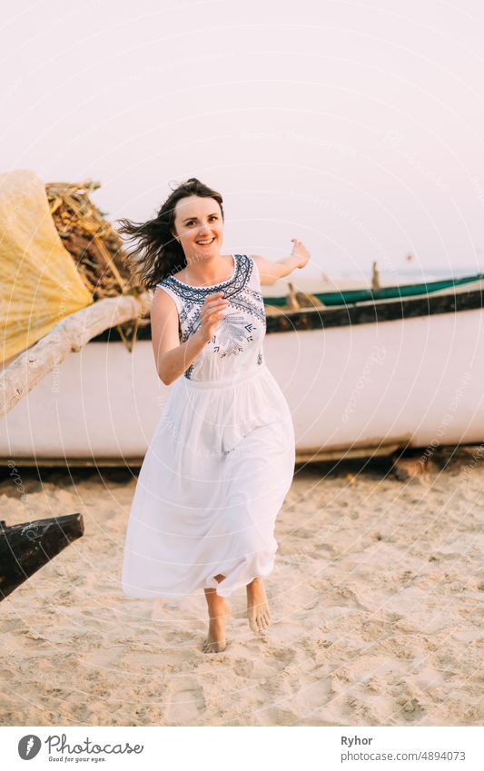 Goa, Indien. Junge kaukasische Frau in weißem Kleid läuft am Strand Sand, genießt das Leben und lächelt aktiv Asien schön Kaukasier das Leben genießen Glück