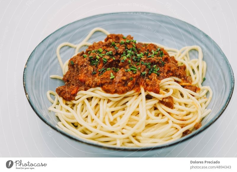 Ein Teller Spaghetti mit Bolognesesoße, ideal für ein Kindermenü appetitlich Hintergrund Basilikum Basilikumblatt Käse klassisch Nahaufnahme gekocht