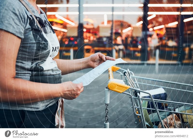 Frau betrachtet die höheren Preise auf der Quittung nach einem Einkauf im Lebensmittelgeschäft. Steigende Preise aufgrund der Inflation. Höhere Rechnungen. Wirtschaftskrise