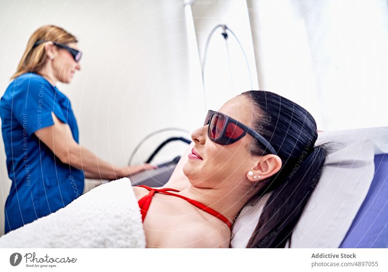 Frau mit Schutzbrille wartet auf Laserepilation Frauen Klient Kosmetikerin warten vorbereiten behüten Epilation Maschine Gerät Salon Verfahren Ästhetik