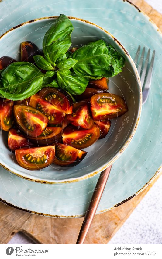 Roher Bio-Tomatensalat mit Basilikumkraut Schalen & Schüsseln Kirschtomate Betontisch Diät Abendessen Essen Lebensmittel frisch Gesundheit Mahlzeit organisch