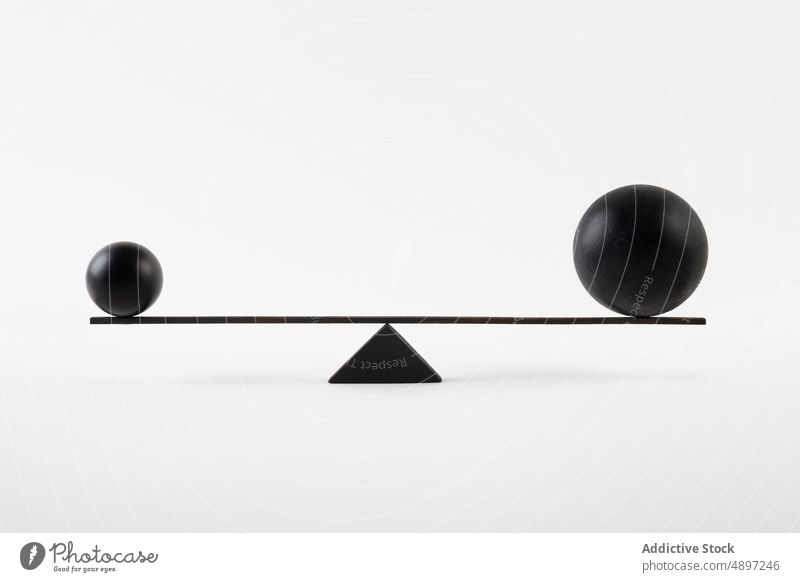 Schwarze Kugeln, die auf einer Waage balancieren Ball Skala Gleichgewicht Geometrie sehr wenige Design Konzept Element modern Kontrast klein groß