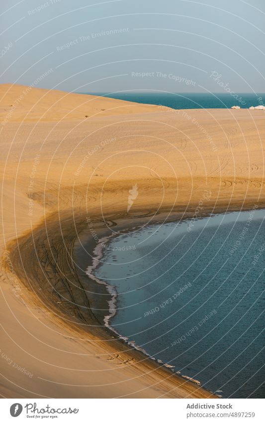 Sandiger, einsamer Strand in Meeresnähe MEER Düne Sommer wüst Blauer Himmel trocknen Seeküste Landschaft doha Katar Küste Ufer Wasser tagsüber friedlich Dürre