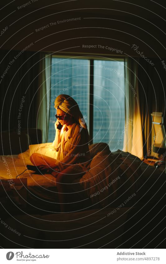 Junge Frau mit Telefongespräch im Hotelzimmer reden Reisender Telefonanruf Bett ernst Feiertag Gespräch zuhören sich[Akk] entspannen Warmes Licht jung