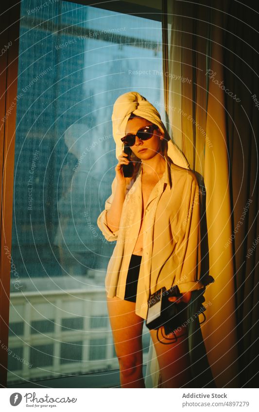 Junge Frau mit Telefongespräch im Hotelzimmer reden Reisender Telefonanruf ernst Feiertag Gespräch zuhören sich[Akk] entspannen Warmes Licht jung Sonnenbrille