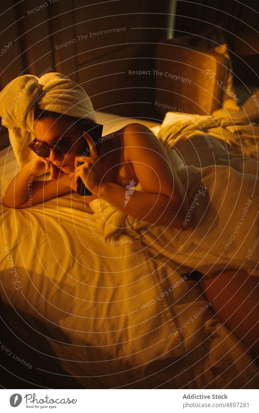 Junge Frau liegt auf dem Bett und telefoniert nach dem Bad reden Smartphone Lügen ruhen ernst Hotel Urlaub sprechen Raum Gespräch Schlafzimmer jung Sonnenbrille