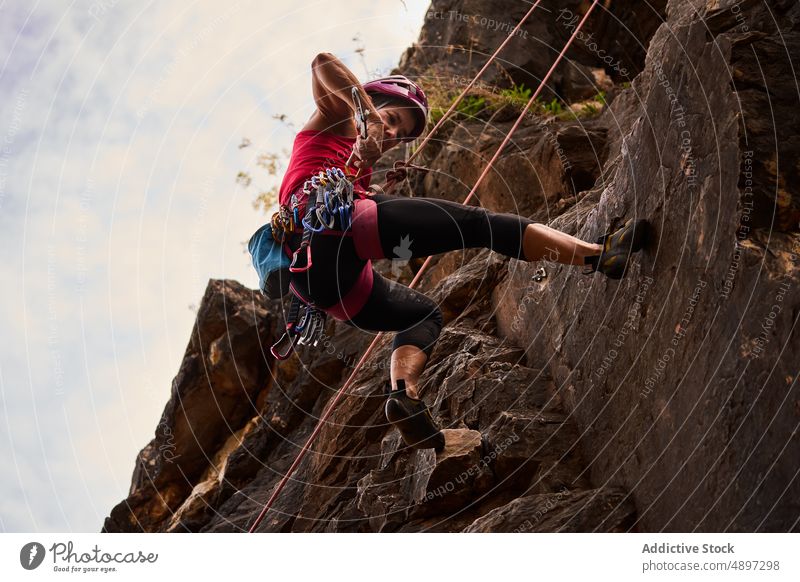 Ältere Frau klettert auf felsigen Klippen gegen den Himmel aktiv Klettern niedriger Winkel Aufsteiger Wanderer Kabelbaum Abenteuer Gefahr Ruhestand wandern